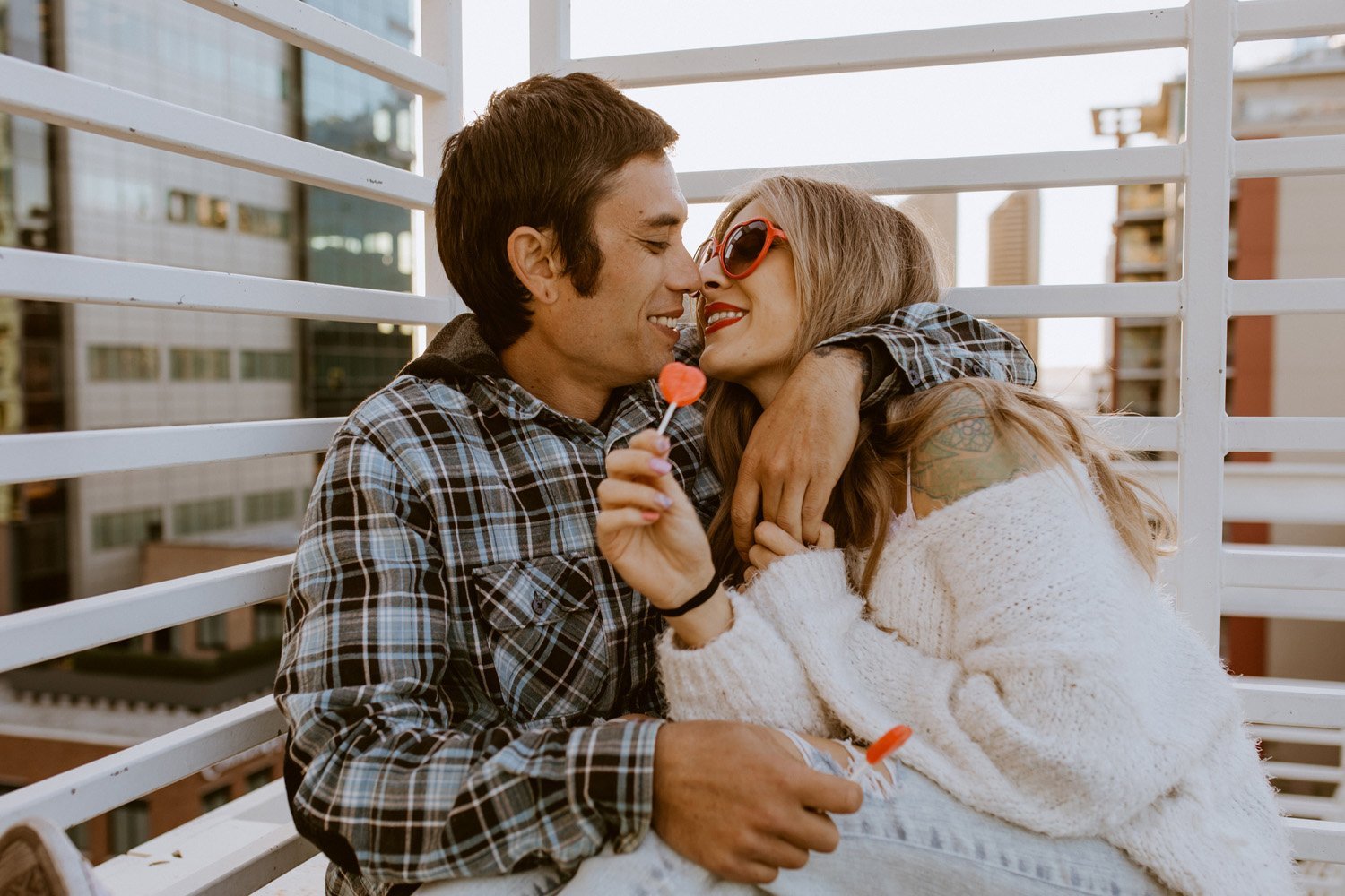 Couple cuddling and eating candy on a rooftop at their Downtown San Diego couples session.