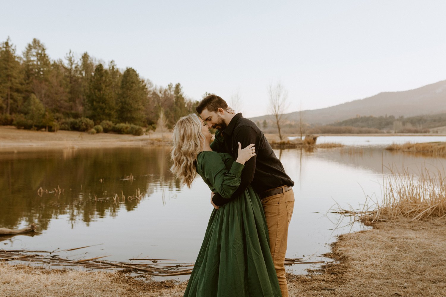 Couple embracing by water at their Lake Cuyamaca engagement session.